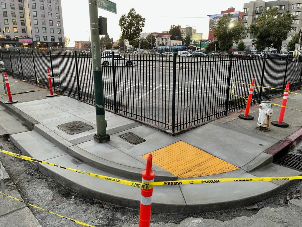 ADA-compliant curb ramp with truncated domes at a street corner, Oakland